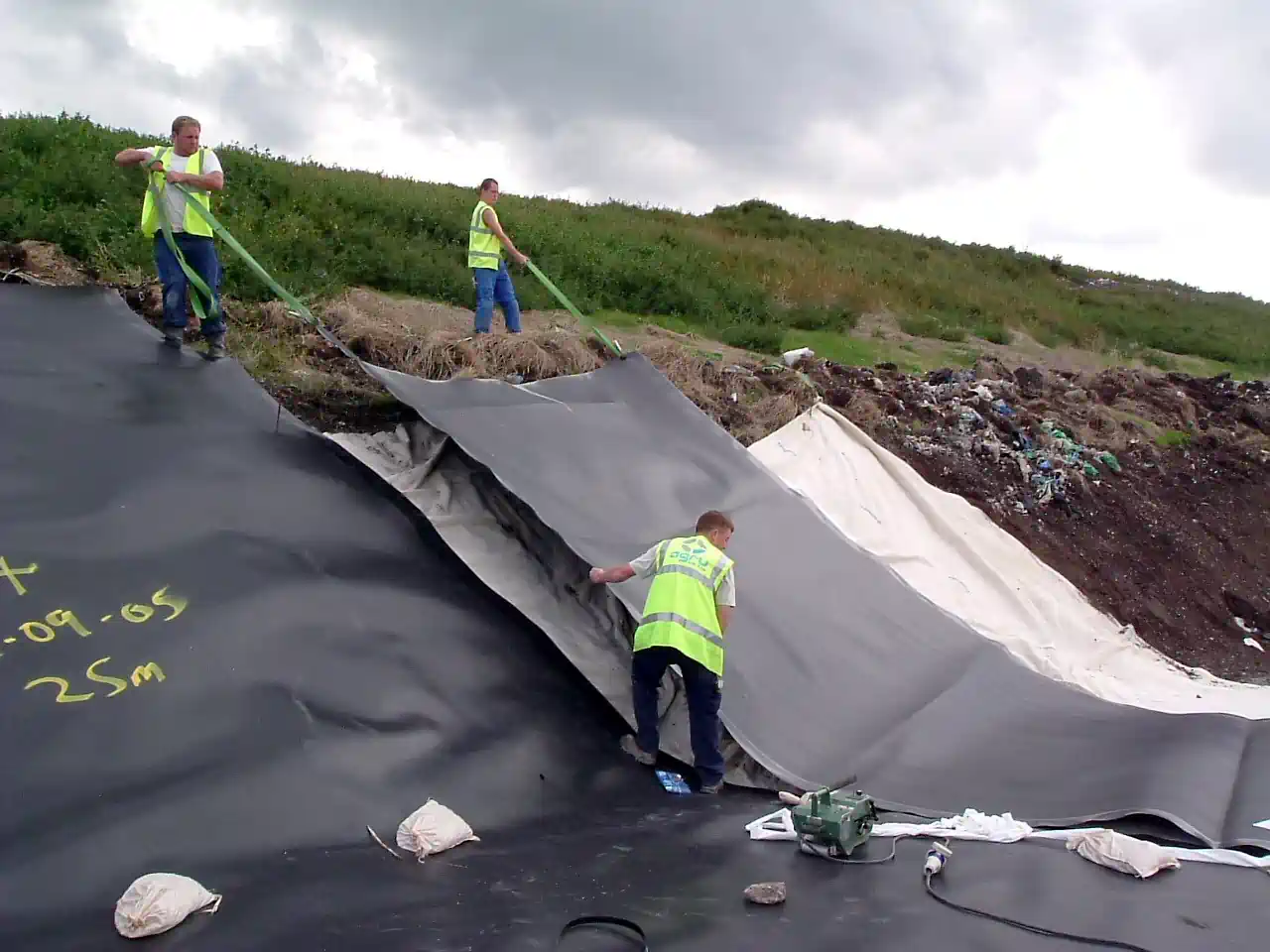 Workmen stretch out a landfill lining geomembrane on one of our landfill restoration projects. Just one of our Landfill Design Consultancy Services.